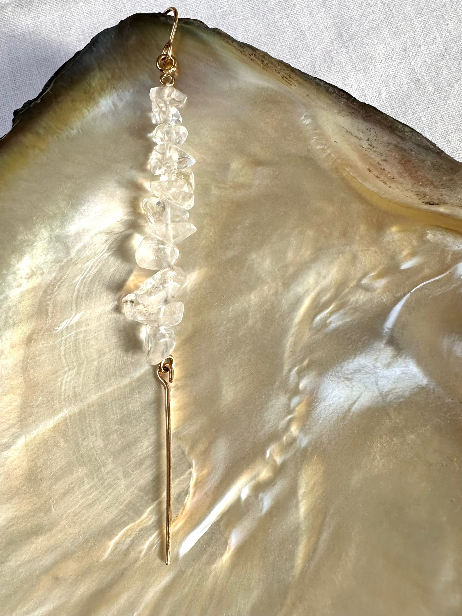 Akari drop earrings, quartz earrings, earrings in gold on shell close-up with quartz looking clear