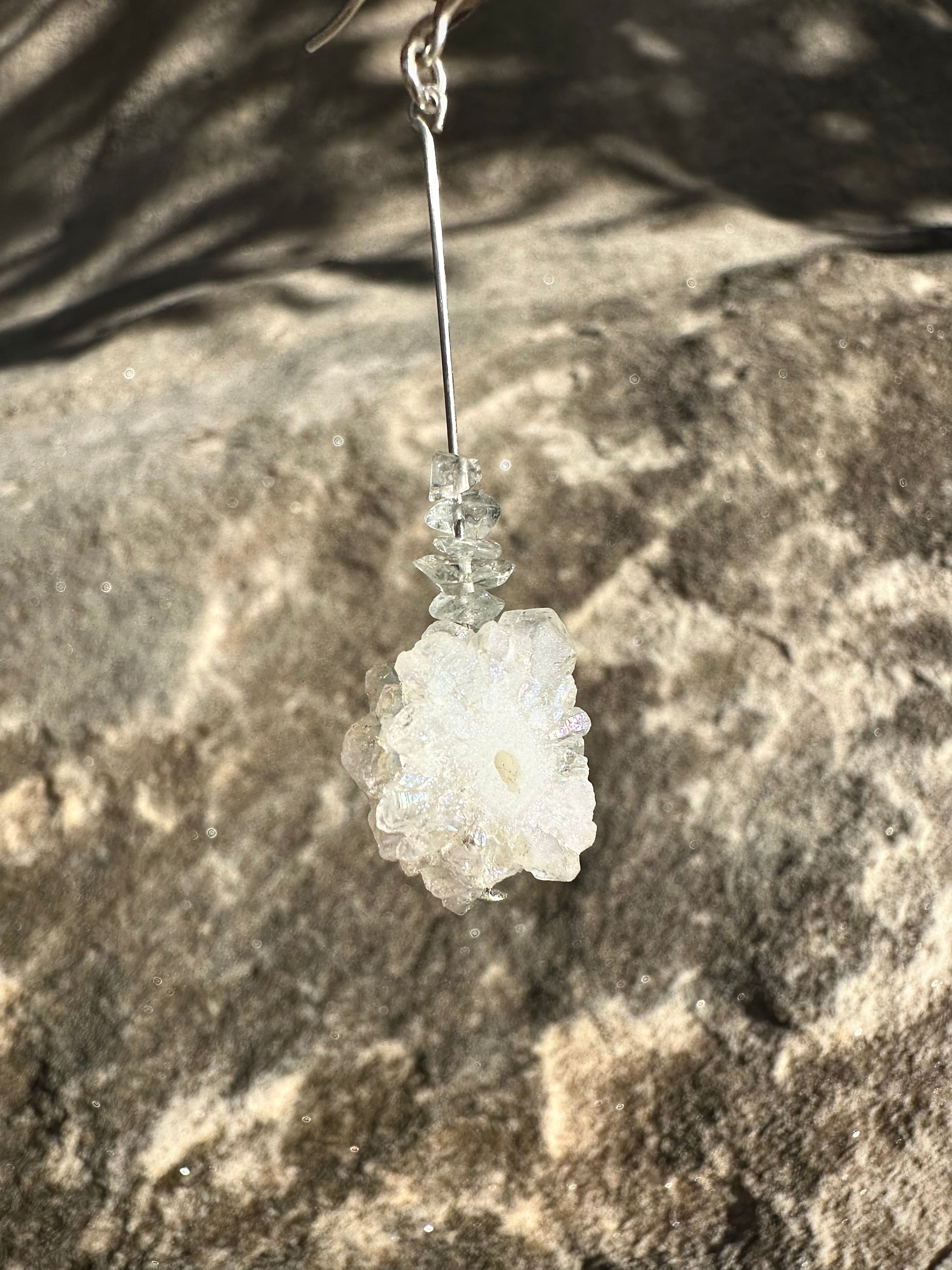 Akamu drop earrings, aquamarine drop earrings, close-up silver earrings in front of rock